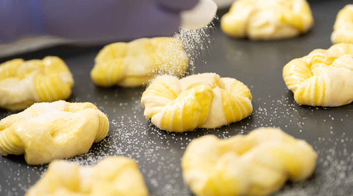 焼成前のパン生地に砂糖をまぶす様子